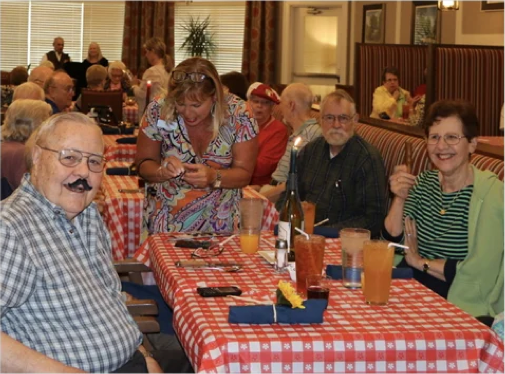 Seniors Smiling While Sitting at Tables with Drinks